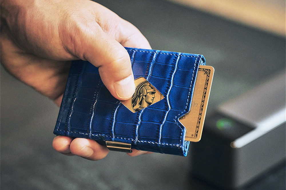 『EXENTRI』はAMEXと提携し、ロゴ入りの別注品が上級会員向けのポイント交換品に。ひし形の窓からAMEXのキャラクター、ケントゥリオの顔がちょうど見えるように収まる｜スキミング防止機能付、１軍カードに直アクセス、コイン・お札も入るコンパクト財布（ウォレット）｜EXENTRI（エキセントリ）