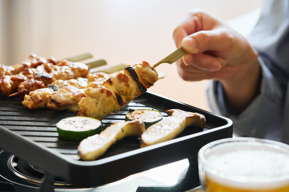 Image: https://1fl0kyr79c.user-space.cdn.idcfcloud.net/photographes/a70b2cadbe3697830e1010ba362b1e30.jpg 食卓にカセットコンロを出して、焼き鳥を焼きながら、ちびちび飲るのもオツな「炭プレート」|万能調理器具「スミイタグリル」・炭(カーボン)プレート|あやせものづくり研究会 Ayase Labo(カーボン加工専門メーカー旭工業)
